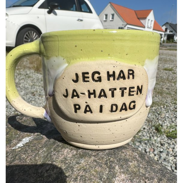 Lysegrn krus med lilla lbeglasur og teksen "Jeg har ja-hatten p i dag"