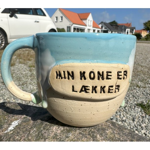 Lyseblå krus med lys grøn løbegalsur og teksten " Min kone er lækker"
