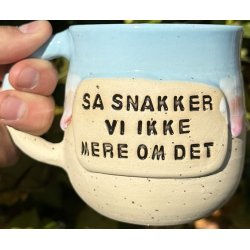 Keramik krus m/hank og citat-tekst "S snakker vi ikke mere om det"