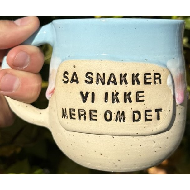 Keramik krus m/hank og citat-tekst "S snakker vi ikke mere om det"